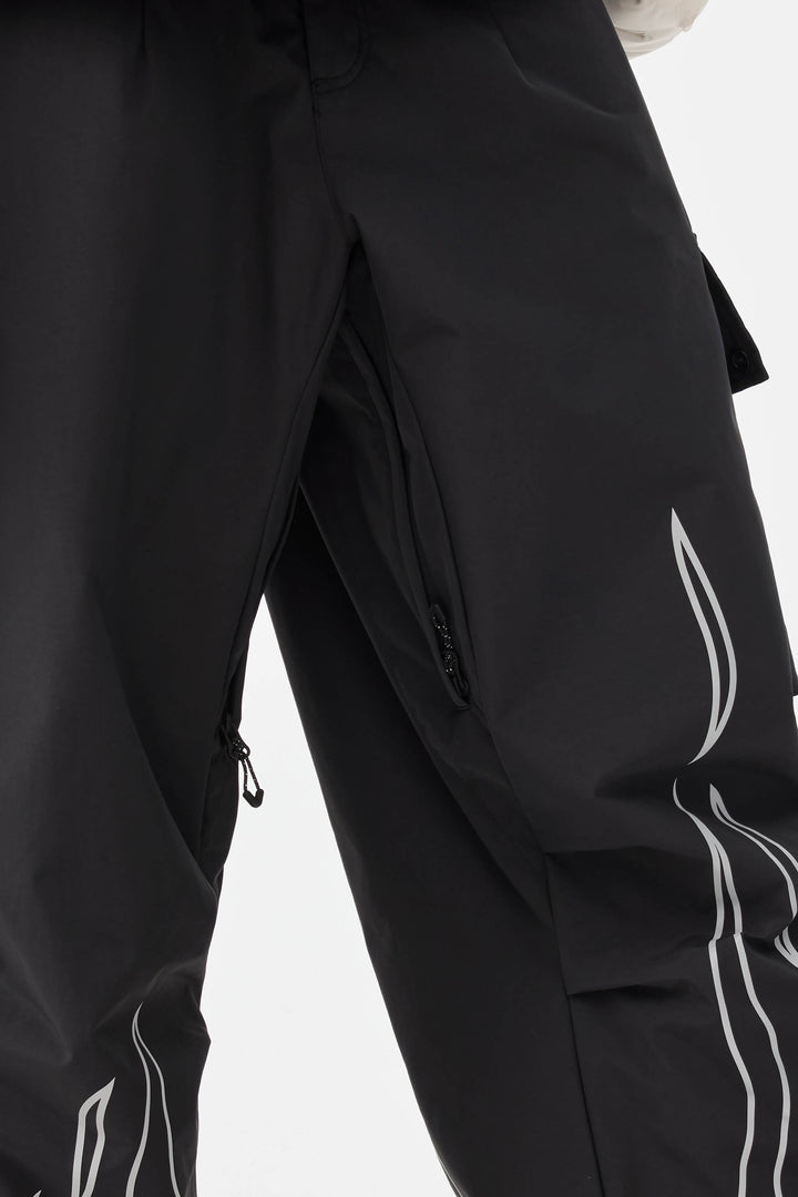 Calça de neve feminina preta com estampa refletiva de chamas, modelo folgado e utilitário.